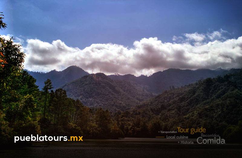 Hilltop viewpoint in Tlatlauquitepec with visitors and partly cloudy sky